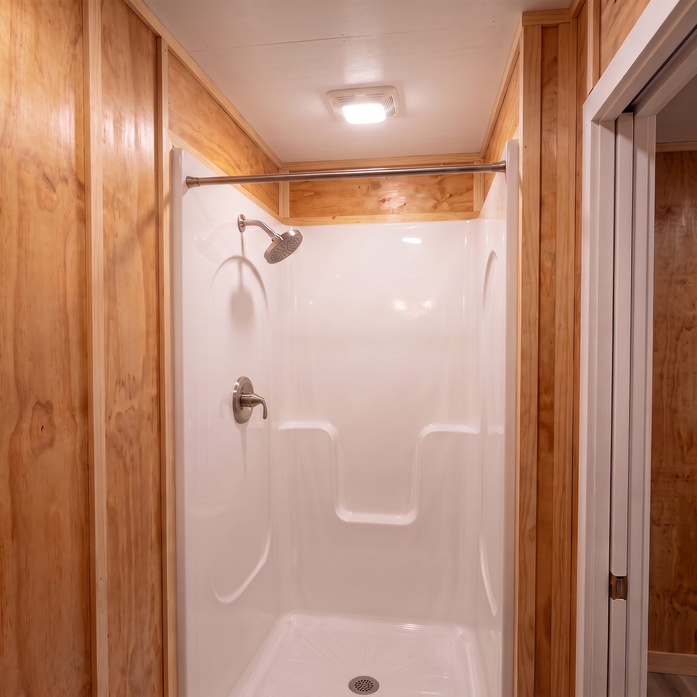 Sport 160 bath with a white molded shower surround and plywood walls